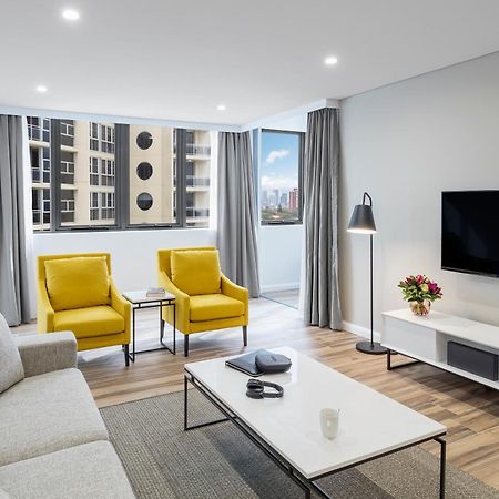 เมอริตัน สวีท บอนดี จังค์ชั่น Hotel ซิดนีย์ ภายนอก รูปภาพ The photo shows a modern, well-lit living room. It features a light gray sofa with a textured fabric. There are two bright yellow armchairs positioned near a window, which allows natural light to enter the space. The room has light gray curtains and 