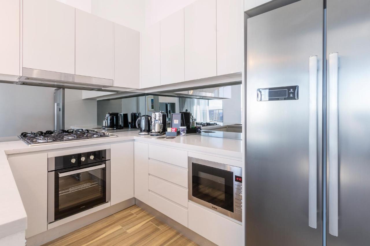 เมอริตัน สวีท บอนดี จังค์ชั่น Hotel ซิดนีย์ ภายนอก รูปภาพ The photo shows a modern kitchen with a clean and minimalist design. It features white cabinetry and a stainless steel refrigerator. The kitchen includes a gas stove with an oven below it, as well as a microwave. There are several kitchen appliances,