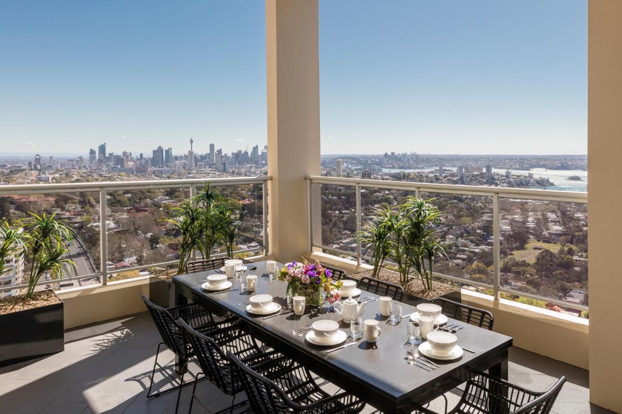 เมอริตัน สวีท บอนดี จังค์ชั่น Hotel ซิดนีย์ ภายนอก รูปภาพ The photo shows a beautifully arranged outdoor dining area on a balcony. There is a long black dining table set for a meal, with plates, glasses, and decorative items like a vase of flowers. Surrounding the table are stylish black chairs. In the back