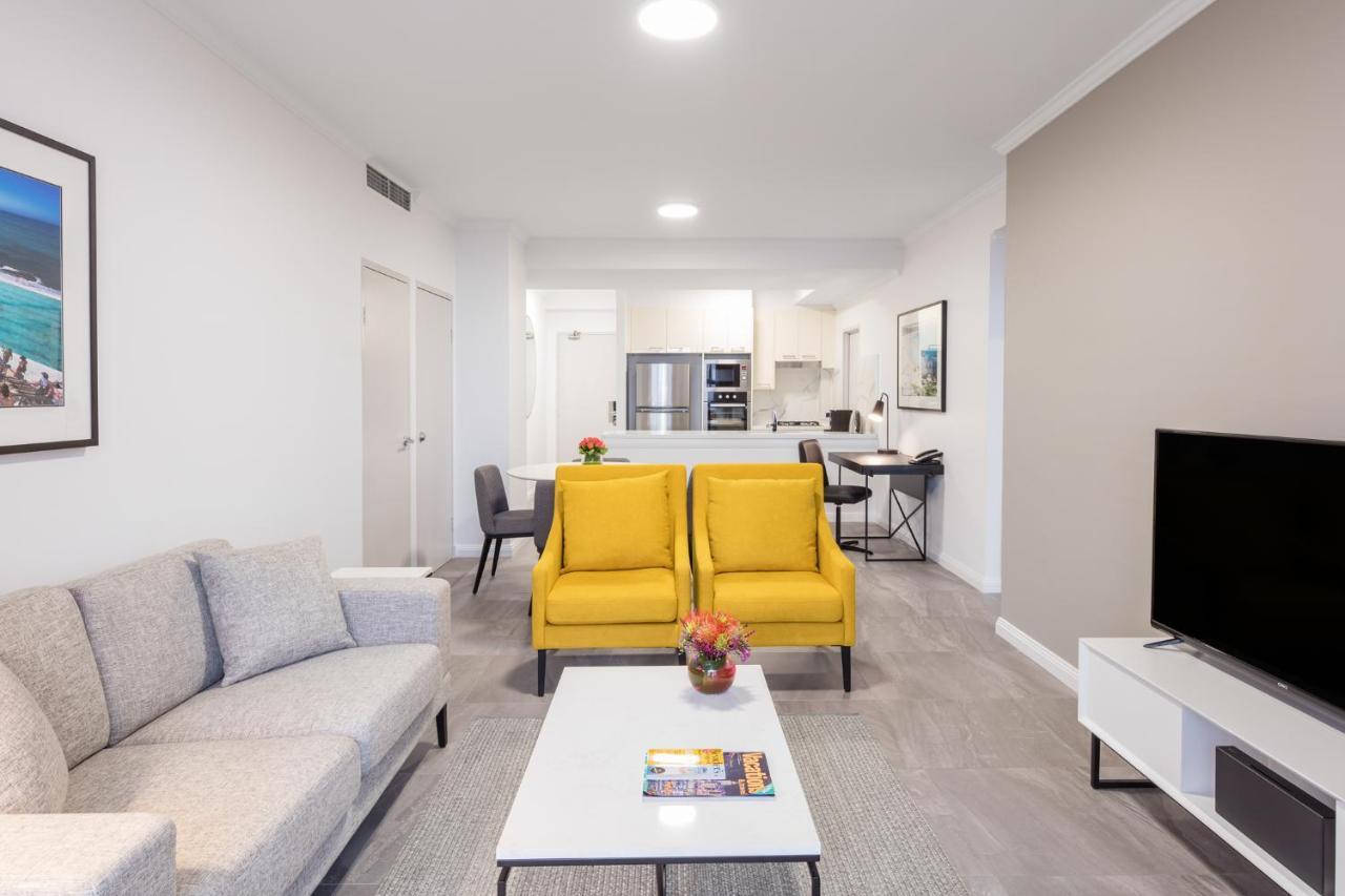 เมอริตัน สวีท บอนดี จังค์ชั่น Hotel ซิดนีย์ ภายนอก รูปภาพ The photo shows a modern living space with a light and airy design. In the foreground, there are two bright yellow armchairs flanking a white coffee table, which has a small vase of flowers and a magazine on it. To the left, there is a light gray sof