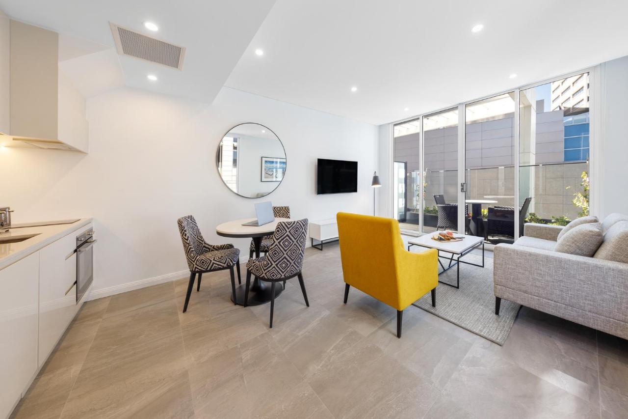 เมอริตัน สวีท บอนดี จังค์ชั่น Hotel ซิดนีย์ ภายนอก รูปภาพ The photo shows a modern and stylish living space. On one side, there is a kitchen area with sleek cabinetry, and next to it, a round dining table surrounded by three patterned chairs. In the center of the room, there is a gray sofa accompanied by a 