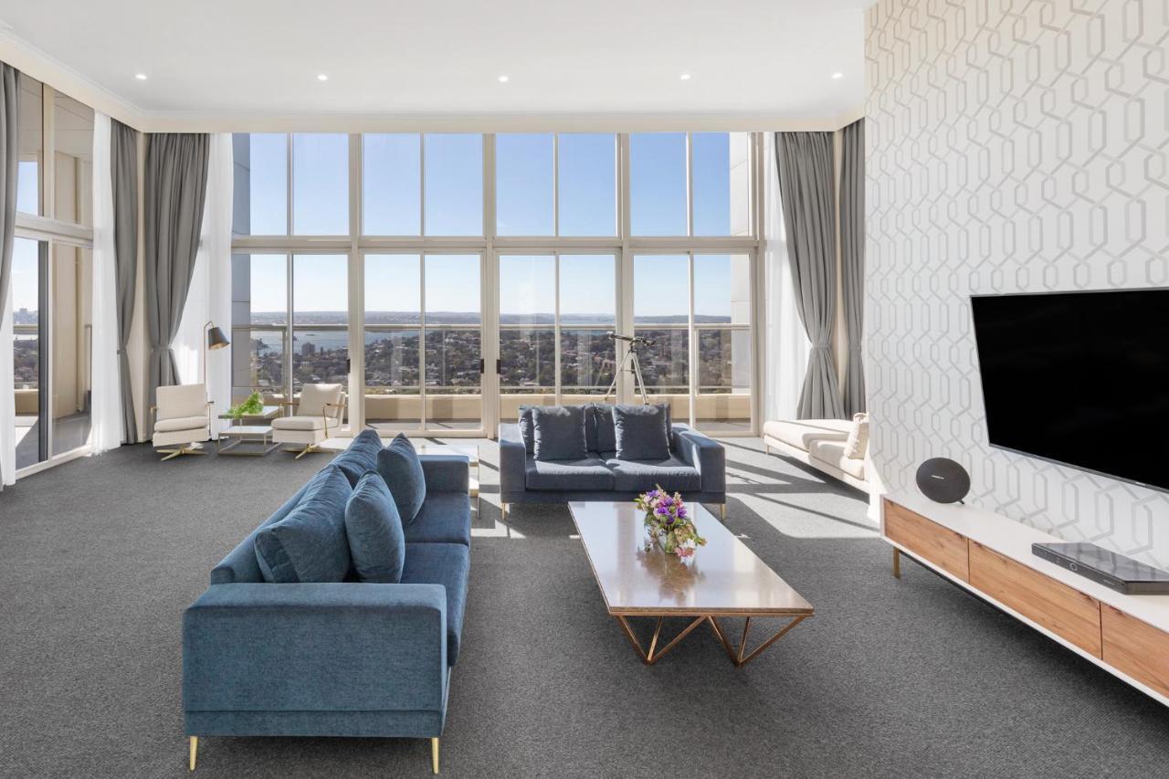 เมอริตัน สวีท บอนดี จังค์ชั่น Hotel ซิดนีย์ ภายนอก รูปภาพ The photo shows a modern and spacious living area. It features large windows that provide a panoramic view of the outside landscape and allow natural light to fill the room. The interior design includes a blue sectional sofa placed in the center, com