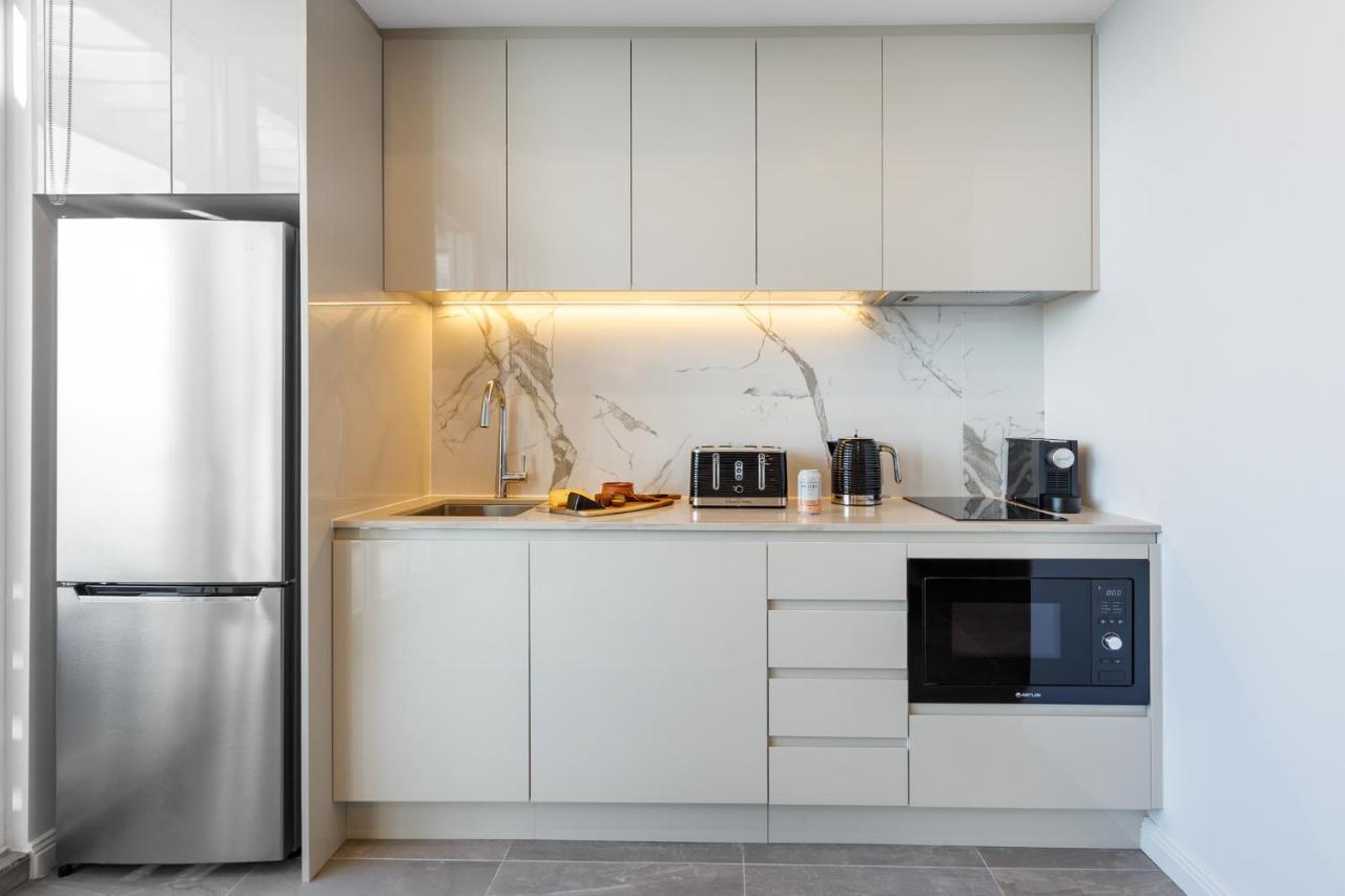 เมอริตัน สวีท บอนดี จังค์ชั่น Hotel ซิดนีย์ ภายนอก รูปภาพ The photo shows a modern kitchen featuring a sleek design. It includes light-colored cabinetry with a smooth finish and upper cabinets that blend seamlessly with the wall. The countertop is made of a light stone, complementing the overall aesthetic. 