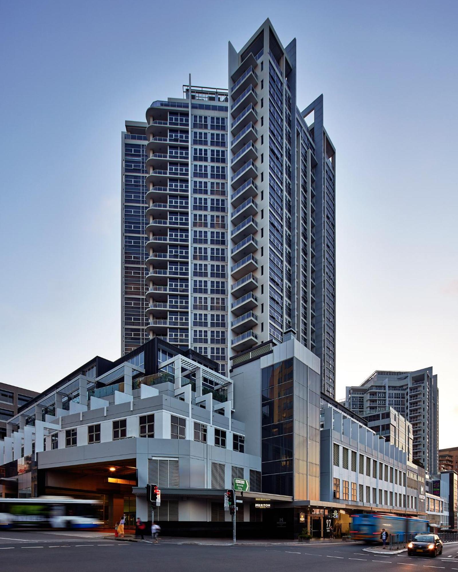 เมอริตัน สวีท บอนดี จังค์ชั่น Hotel ซิดนีย์ ภายนอก รูปภาพ The image shows a modern high-rise building with a sleek design. The structure features a mix of glass and concrete elements, with multiple levels showcasing balconies. The building appears to be part of an urban environment, likely containing reside